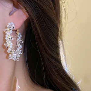 Close-up of elegant crystal and pearl beaded hoop earrings on model.
