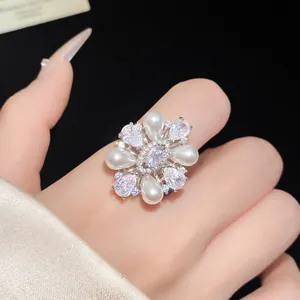 Vue détaillée d'une bague fleur vintage en zircon et perles sur le doigt