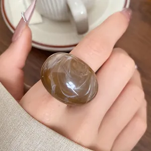 Close-up view of a marbled brown resin ring featuring unique white swirl patterns.