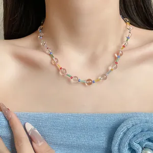 Detailed view of a colorful beaded necklace with clear glass beads on a female neck.