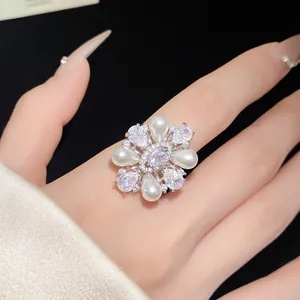 Gros plan d'une élégante bague fleur avec perles et zircons sur le doigt d'un mannequin.