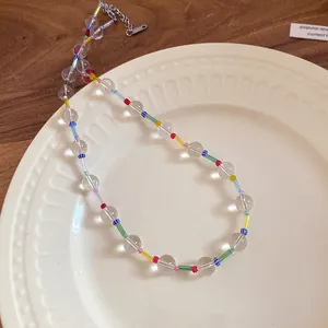 Close-up detail of colorful beaded necklace with clear round beads on a ceramic plate