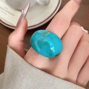 Close-up detail of a large turquoise marbled resin statement ring on a female hand