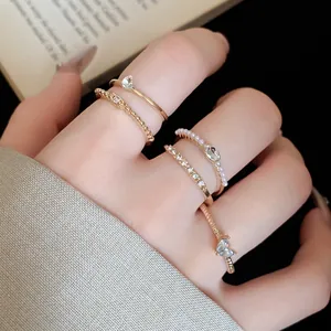 Nahaufnahme von minimalistischen Goldringen mit Perlen und Strass an den Fingern.