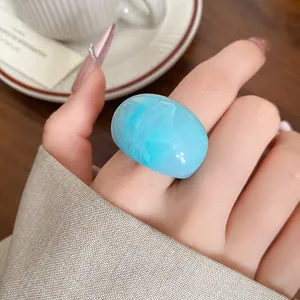Macro detail of a chunky blue marbled resin ring with a high-gloss finish on a finger