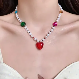 Close-up of a sweet freshwater pearl necklace featuring colorful beads and a red heart pendant.