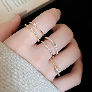 Detailansicht eines 5-teiligen goldenen Ringsets mit Strass und Perlen an den Fingern
