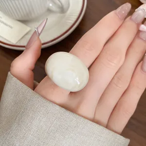 Close-up of a resin marbled ring worn on a finger with a lifestyle background