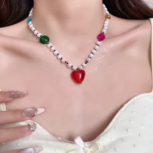 Detail view of a sweet freshwater pearl necklace with a vibrant red heart pendant