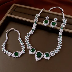 Detailed view of luxury jewelry set with emerald green zircons and silver finish.