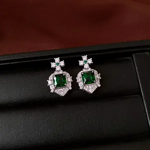 Detailed view of emerald green square zircon earrings presented in a luxury jewelry box.