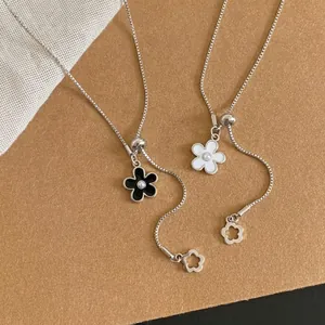 Collana regolabile a fiore in smalto bianco e nero, catena sottile argentata elegante.
