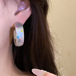 Gros plan détaillé de créoles en résine à pois colorés sur un mannequin pour l'été