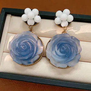 Orecchini vintage con rosa in resina blu e perline bianche in un portagioie