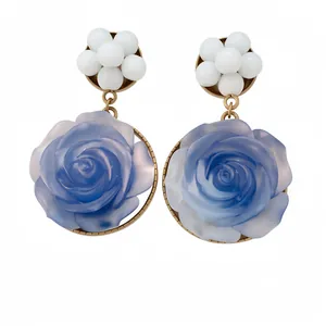 Orecchini vintage in resina con rosa blu e accenti di perle bianche su sfondo bianco.