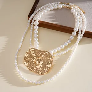 Close-up of multi-layer pearl necklace with statement hammered gold metal pendant