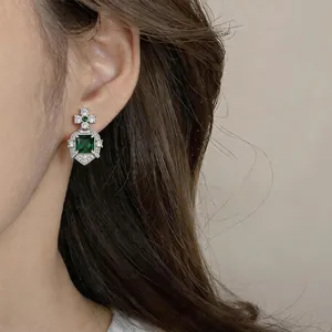 Close-up of vintage style palace earring featuring square emerald green zircon on model's ear