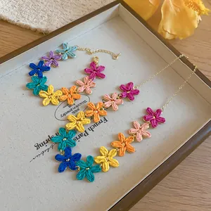 Set collana e bracciale con fiori colorati in rafia esposto in vassoio portagioielli