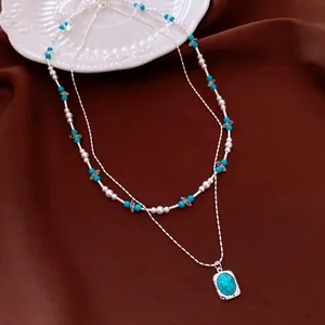 Detail view showing a vintage layered necklace with turquoise stones and white pearls.