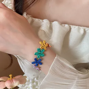 Primo piano di un braccialetto di fiori in rafia colorata sul polso con abito plissettato
