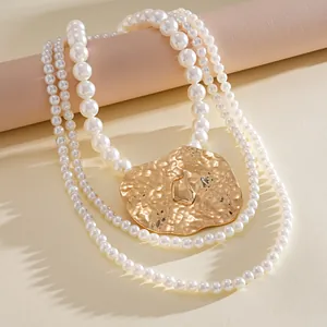 Macro view of multi-layer white pearl necklace featuring a large textured gold pendant