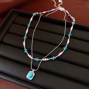Close-up of double-layer necklace with glass pearls and turquoise stone pendant