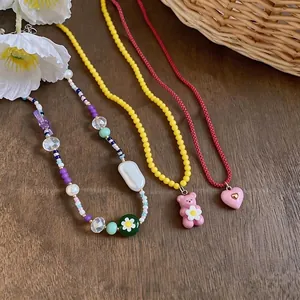 Colorful beaded necklaces with bear, flower and heart charms on a wooden background