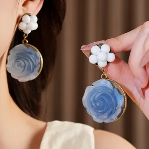 Primo piano di orecchini vintage con rosa in resina blu e grappoli di perline bianche