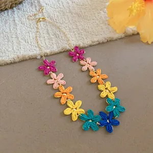 Dettaglio di una collana fatta a mano con fiori di rafia colorati e catena dorata