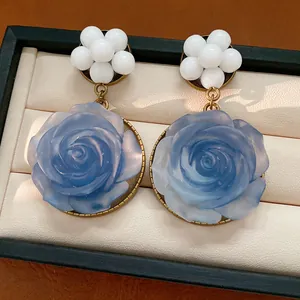 Dettaglio ravvicinato di orecchini a rosa in resina blu vintage con grappoli di perline.