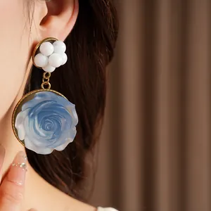 Primo piano dettagliato di un orecchino vintage in resina con rosa blu e perle bianche