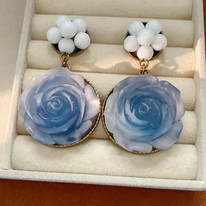 Dettaglio orecchini a rosa in resina blu con grappoli di perline in stile vintage.