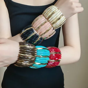Detail showing stacked marbled acrylic bangles with gold-tone accents on wrist