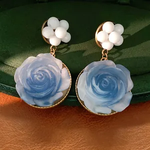 Primo piano dettagliato dei petali di rosa blu in resina e dei grani di perle bianche su questi orecchini
