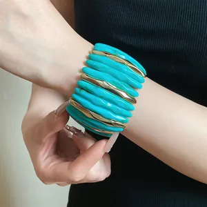 Close-up of a stylish turquoise marbled acrylic bracelet with elegant gold segments on a model