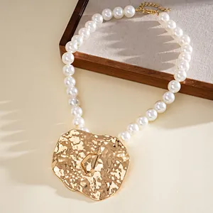 Close-up of pearl necklace with a large textured gold pendant on a display stand