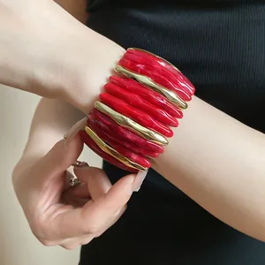 Stylish chunky red acrylic marble bracelet with elegant gold accents shown on a model wrist