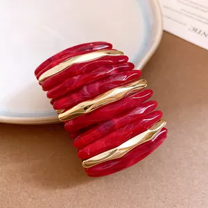 Detailed macro view of red marbled acrylic bracelet with sleek gold-tone metal accents