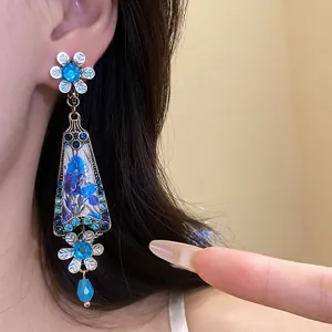 Vintage blue resin floral drop earrings with rhinestones worn by a model in a close-up view