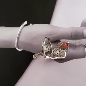 Detailed view of artistic leaf shaped ring with sparkling zircons and matching silver bangle.