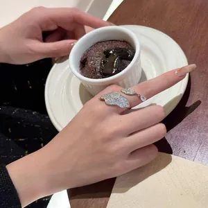 Close-up of elegant fallen leaf shaped silver ring with sparkling zircons worn on finger