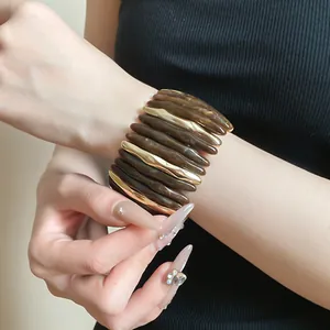 Detail view of a marbled acrylic and gold-tone metal chunky stretch bracelet on wrist