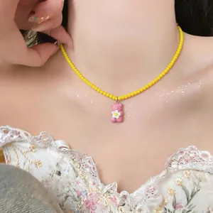 Close-up of a sweet yellow beaded necklace featuring a pink resin gummy bear pendant