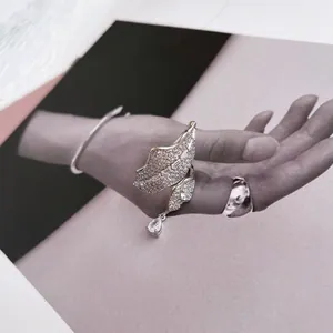 Close-up of a sparkling leaf-shaped zircon ring with pear-cut drop on magazine background.