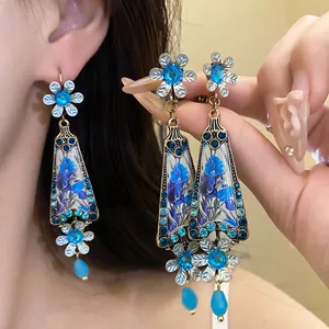 Macro view of vintage style blue floral resin pendant earrings with rhinestone accents