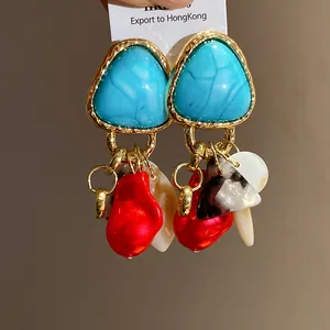 Primer plano de pendientes vintage con borlas, turquesa y detalles de concha