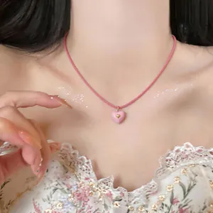 Detailed view of a sweet pink heart resin pendant necklace with a braided cord strap.