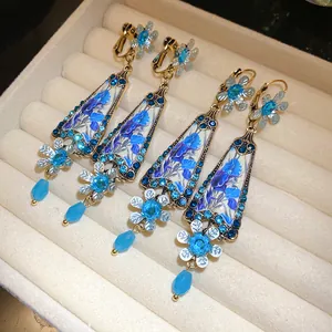 Detailed view of vintage blue floral resin earrings with sparkling rhinestones in a tray.