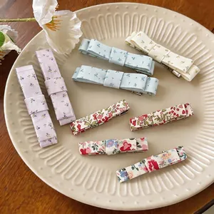 Collection of various floral print fabric bow hair clips on a vintage decorative plate