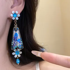 Close-up detail of vintage floral dangling earrings with blue resin and rhinestones.